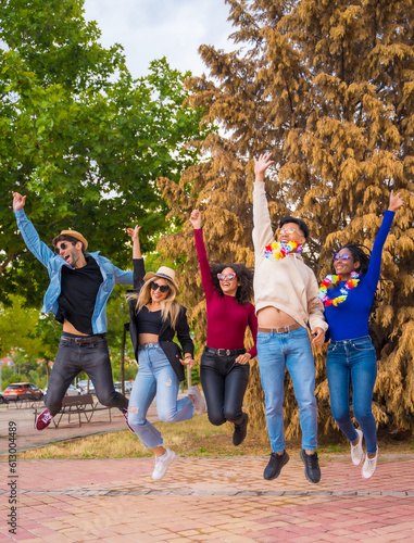 Group of multi ethnic friends partying in a park - Diverse young people jumping for joy at a summer party - Happy hour, lunch break and youth concept