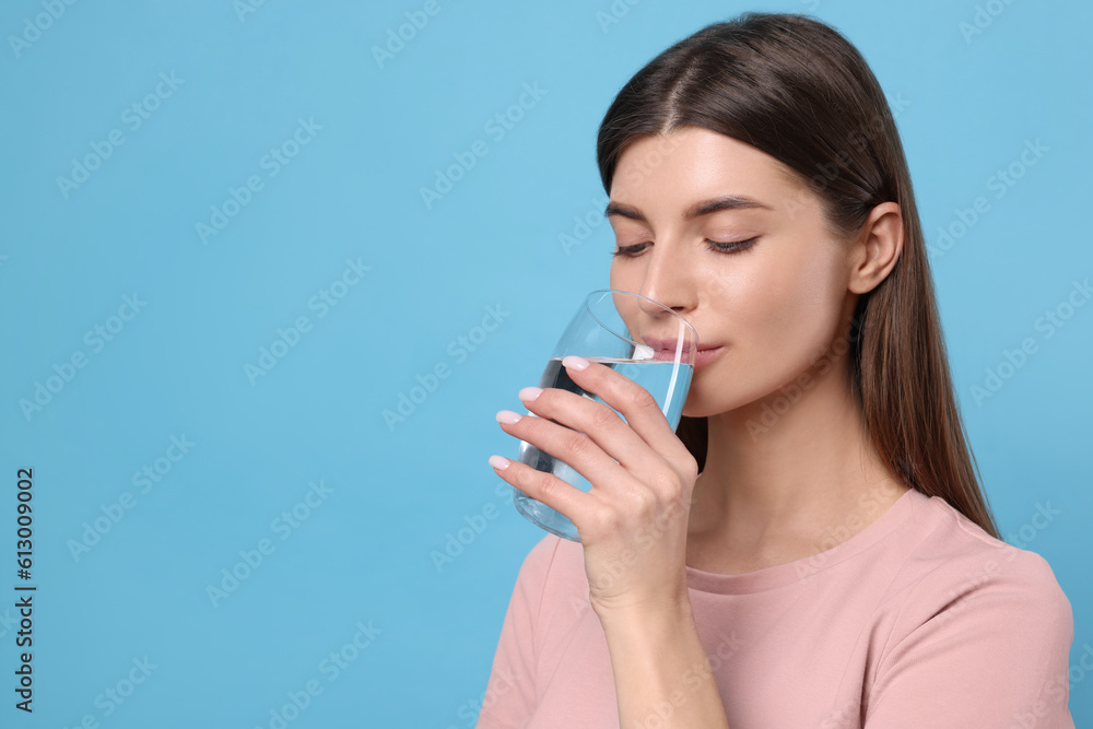 Healthy habit. Woman drinking fresh water from glass on light blue background. Space for text Healthy habit. Woman drinking fresh water from glass on light blue background. Space for text