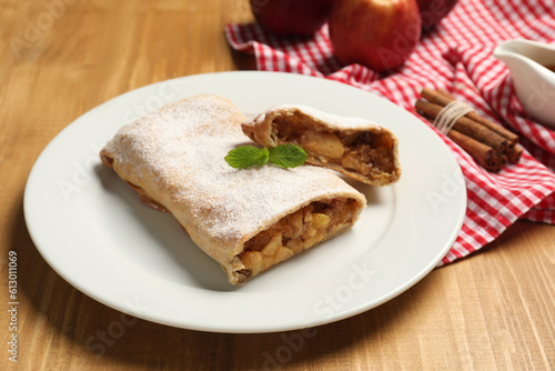 Delicious strudel with apples, nuts and raisins on wooden table, closeup