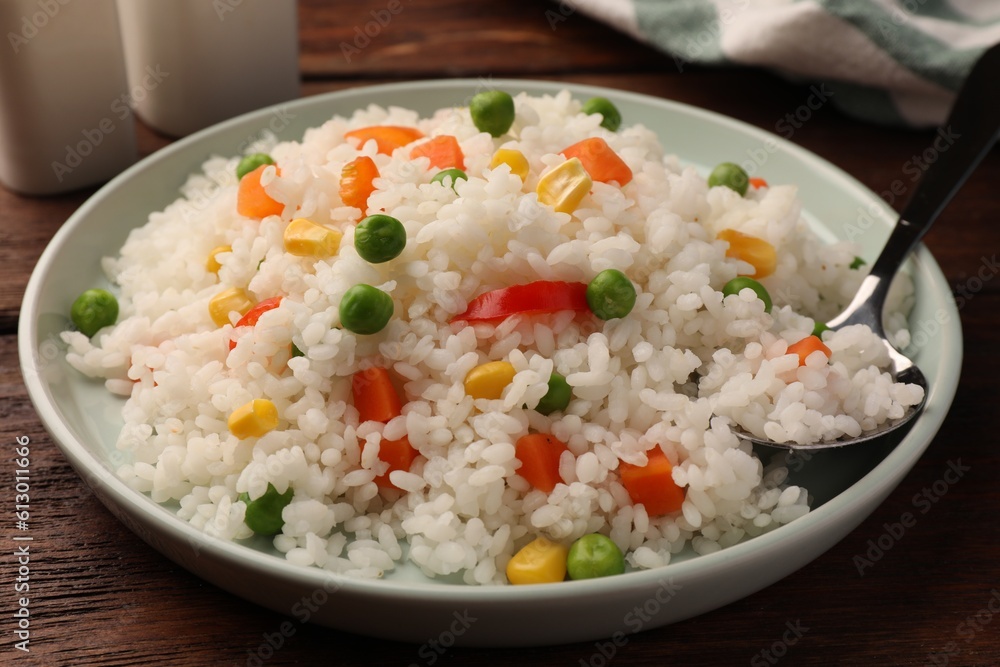 Delicious rice with vegetables served on wooden table, closeup Delicious rice with vegetables served on wooden table, closeup