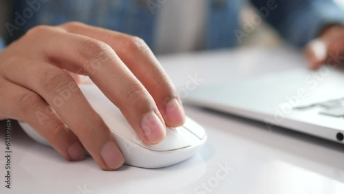 Close-up of businesswoman hand using mouse on laptop computer. Woman is working with laptop sit in home office room.