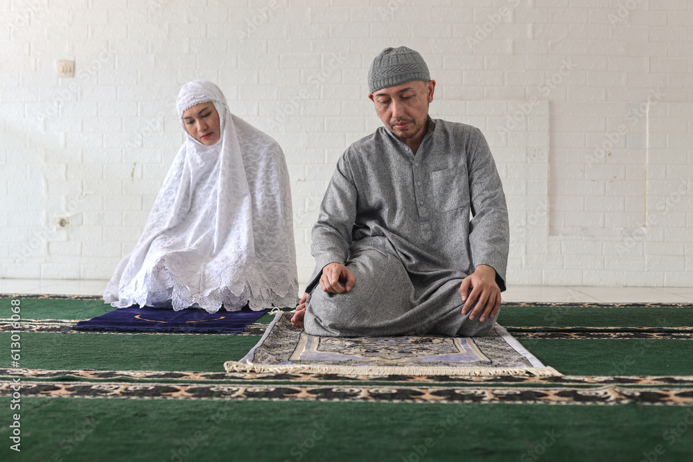 Asian Muslim man imam and leading his wife to pray, doing one