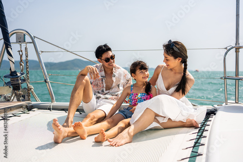Caucasian happy family sitting on deck of yacht while yachting outdoor. © Kawee