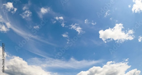 Beautiful blue summer sky with white clouds moving slowly. Soft fluffy cloudscape changing shape from low angle view. photo