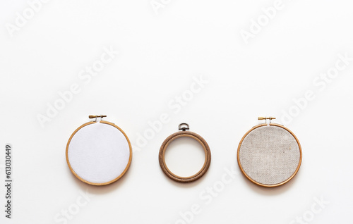 Wooden and plastic hoops for hand embroidery with different types of canvas: linen canvas with square holes for cross stitch, with transparent mesh and cotton felt on white background. Copy space