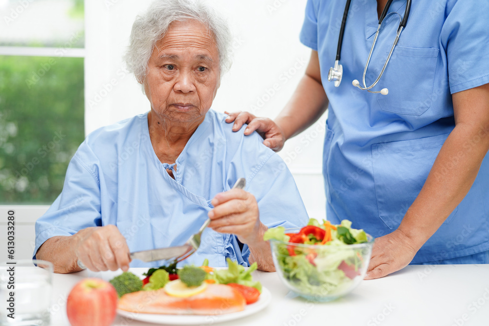 Asian elderly woman patient eating salmon stake and vegetable salad for healthy food in hospital. Asian elderly woman patient eating salmon stake and vegetable salad for healthy food in hospital.