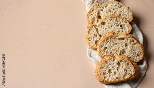 Sliced sourdough bread on a linen towel. Fresh homemade artisan bread, organic bakery products. Banner with copy space on beige background. photo