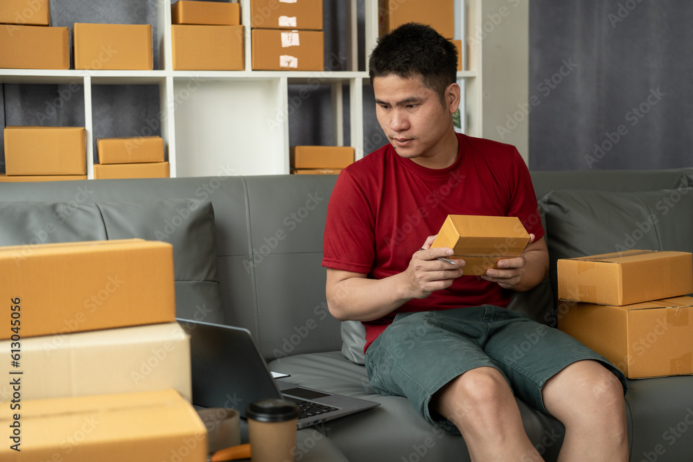 Happy asian man customer opening cardboard box parcel on sofa. Happy asian man customer opening cardboard box parcel on sofa.