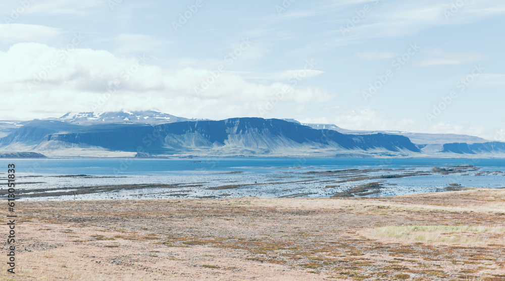 vue sur une plage avec un cours d'eau et une montagne en arrière plan lors d'une journée d'été ennuagée