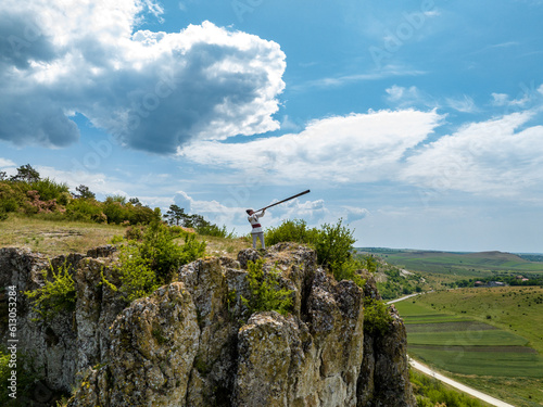 aerial view of a man in traditinal moldavian outfit playing on bucium on top of a rock on high altitude photo