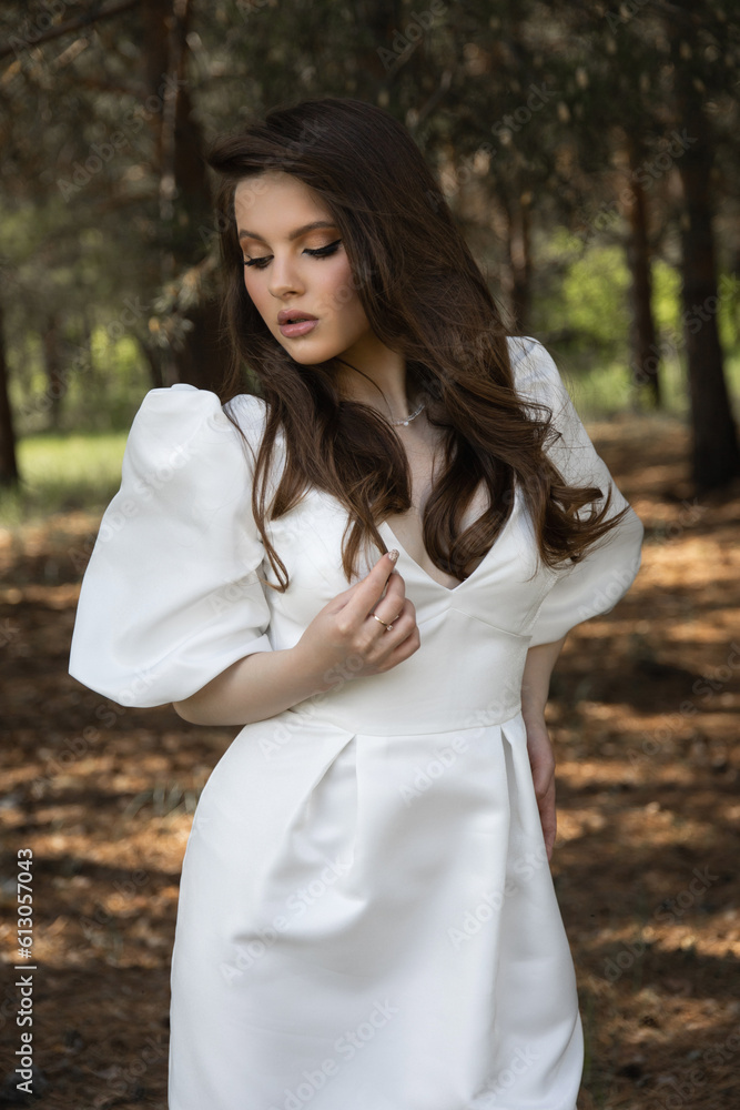 Beautiful caucasian brunette girl in a wedding dress in the forest Beautiful caucasian brunette girl in a wedding dress in the forest