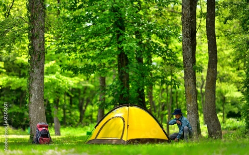 新緑の森でテントキャンプを楽しむ男性