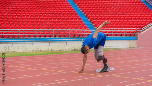 asian athlete equipped with two prosthetic running blades in ready at starting blocks. preparing to sprint off on running track of sports stadium, determination and resilience