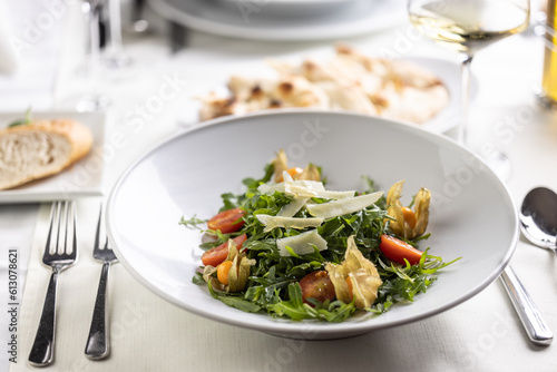 Table set for a lunch or dinner with rocket salad with tomatoes, physalis and parmesan