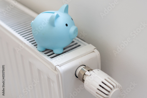 Pig piggy bank and dollar bills on a radiator indoors close-up. Heating concept.