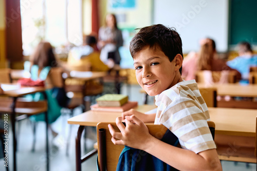 Happy elementary student in classroom looking at camera.