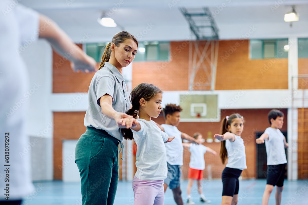 Hispanic elementary student exercising with help of her sports teacher during PE class. Hispanic elementary student exercising with help of her sports teacher during PE class.