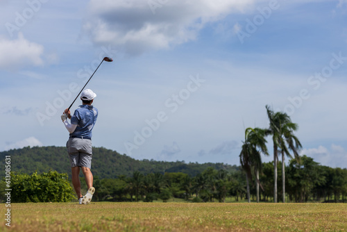 Golfer he's golfing in sunlight. View from the back. Backswing on teeing ground.