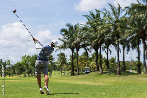 Golfer he's golfing in sunlight. View from the back. Backswing on teeing ground.