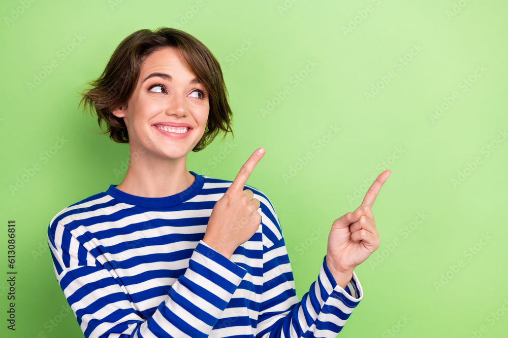 Photo portrait of nice interested girl direct fingers empty space novelty product proposition wear shirt isolated green color background Photo portrait of nice interested girl direct fingers empty space novelty product proposition wear shirt isolated green color background