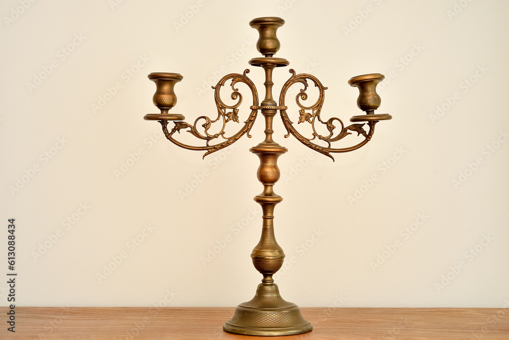 Rustic candlestick on the brown wooden dresser. Vintage candle holder without candles. 