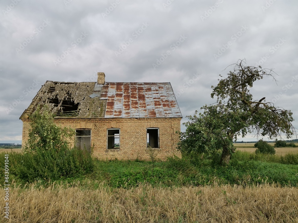 Obraz premium Old brick farmhouse in the countryside with storm clouds in the sky.