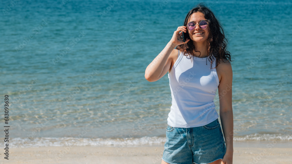 young woman tourist on the beach using mobile phone young woman tourist on the beach using mobile phone