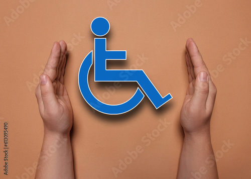 Disability inclusion. Woman protecting wheelchair symbol on coral background, closeup