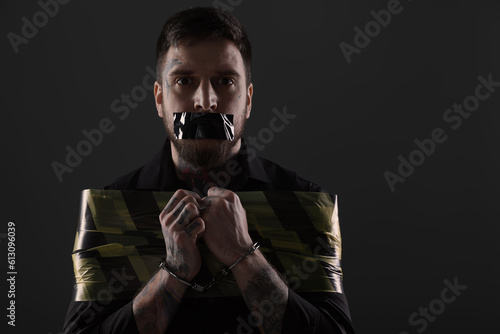 Canvas Print Man taped up and taken hostage on dark background. Space for text