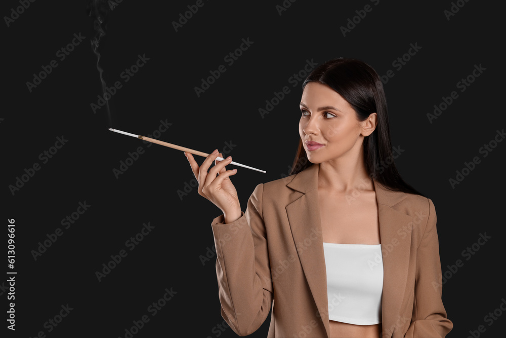 Obraz premium Woman using long cigarette holder for smoking on black background