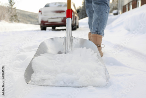 Woman removing snow with shovel outdoors, closeup