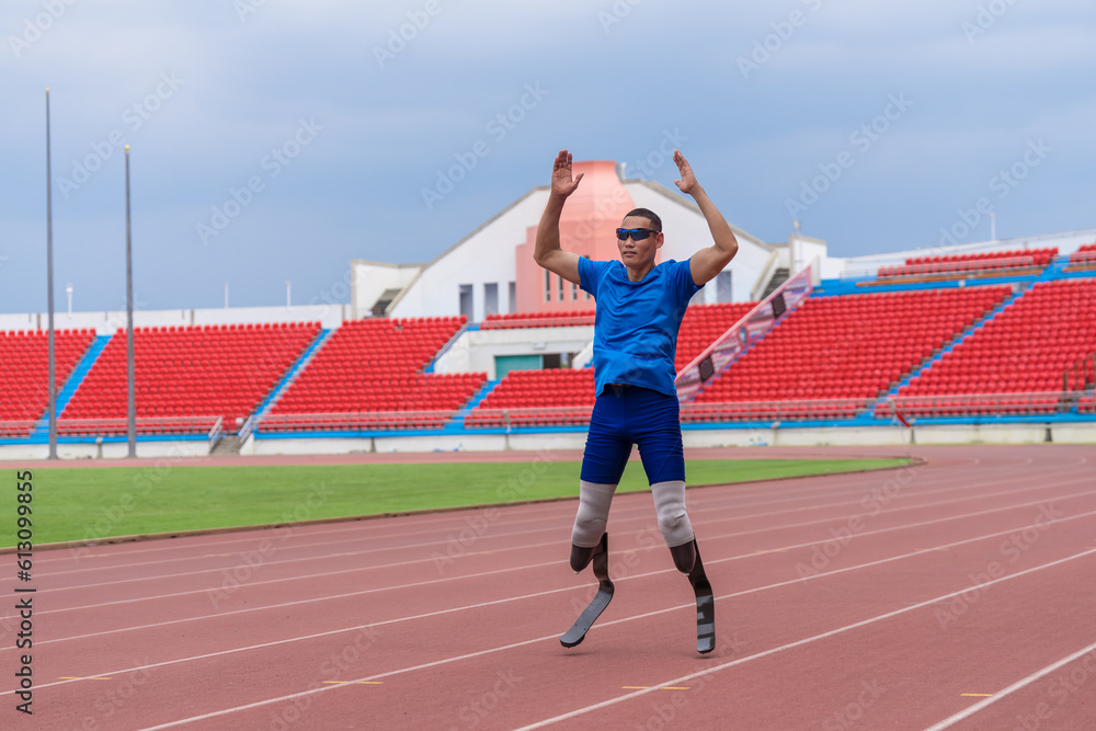 An Asian athlete with prosthetic running blades, fires up with a jump slap as part of his warm-up routine at the stadium