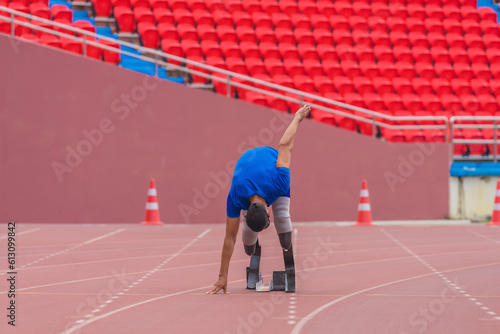 Asian athlete at start block, ready to speed run on the stadium track with prosthetic running blades