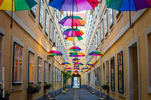 Colorful umbrellas decorating a narrow street, between old European yellow buildings. Colored umbrellas sky making a festive, fun, setting in Vienna, Austria. Happy, colorful, and pride concept.