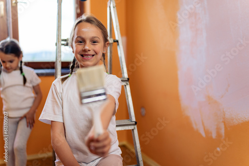a young girl smeared with paint poses with a brush in her hand