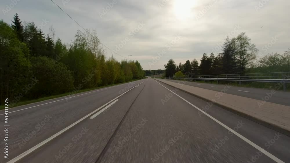 The road winds through expansive fields and charming villages, with trees lining its sides. Cars traverse the path, blending into the rustic countryside scenery. The road winds through expansive fields and charming villages, with trees lining its sides. Cars traverse the path, blending into the rustic countryside scenery.