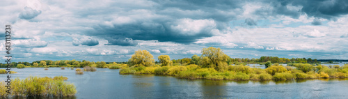 Fototapeta Naklejka Na Ścianę i Meble -  Panoramic View Countryside Landscape During Spring Flood Floodwaters. Tranquil Bold Bright Blue Sky Above Nature Landscape During Spring Flood. Amazing Reflections In River. Musical Calmness Concept.