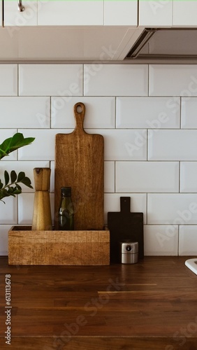 Kitchen brass utensils, chef accessories. Hanging kitchen with white tiles wall and wood tabletop.Green plant on kitchen background