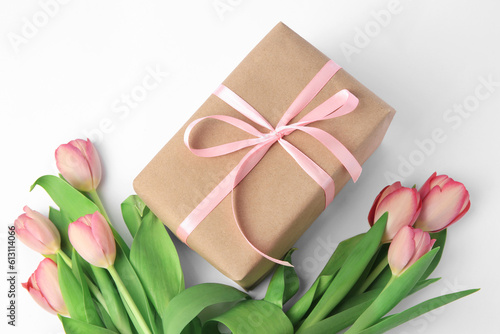 Beautiful gift box with bow and pink tulips on white background, above view