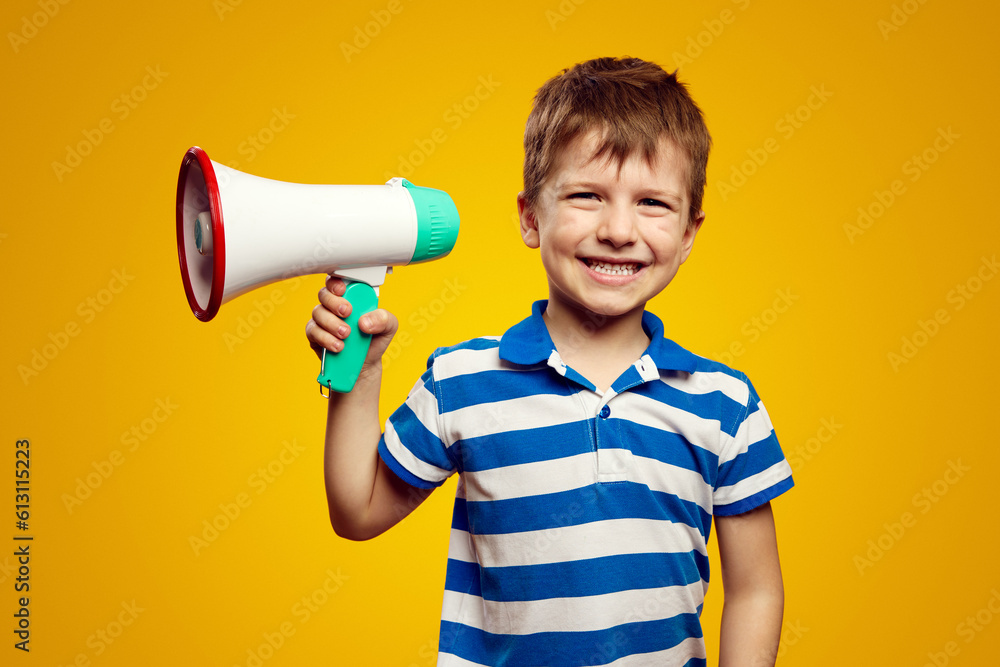 Naklejka premium Little small boy wearing blue striped shirt, scream in megaphone announces discounts sale Hurry up isolated on yellow background studio