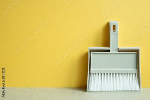 Gray broom and dustpan on gray table. yellow background. Cleaning housework concept. copy space photo