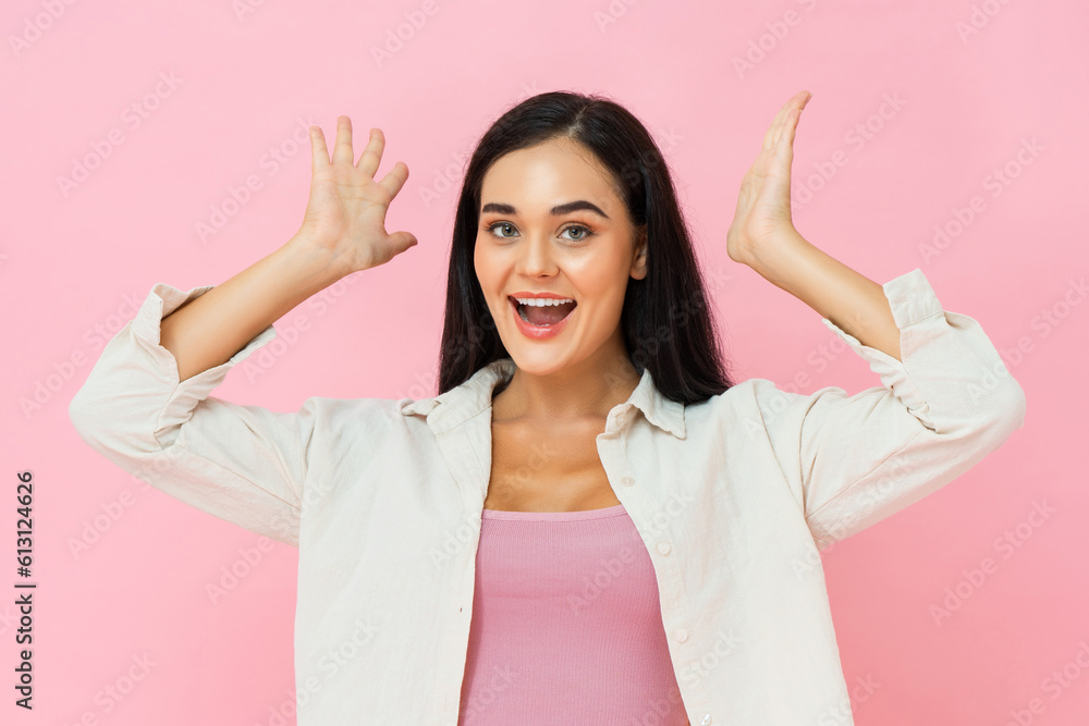 Surprised pretty Asian woman smiling with hands up in pink color isolated background studio shot