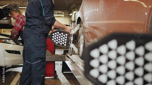 CLose-up car wheel indoors service maintenance repair center against laser sensor equipment diagnostics and 3d wheel alignment. Vehicle inside garage workshop for auto camber toe check fixing.