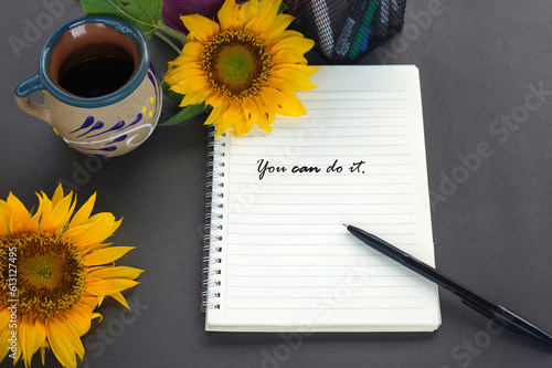 Motivational words on a notebook - You can do it. With pen, sunflowers and a cup of coffee.  photo