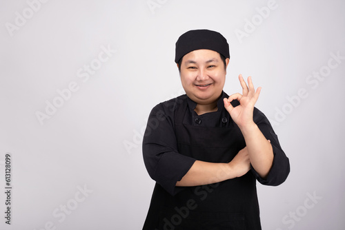 Portrait of smiling chef wearing uniform on gray background.