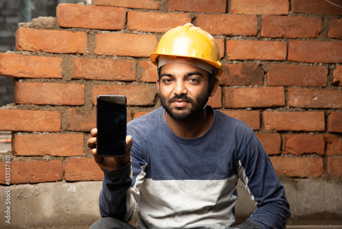 Принти на полотні indian construction worker or daily wage labour using mobile phone at site