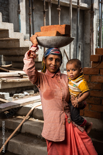Asian Indian woman labour or coolie working at construction site Carrying bricks on her head.