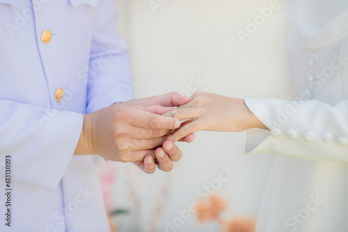 muslim groom in white dress wear wedding rings to left ring finger of muslim bride.concept for wedding card background, poster,Invitation card © Kajanan