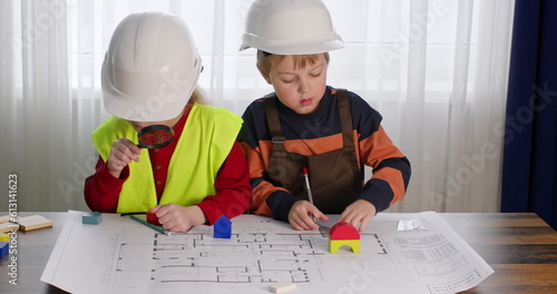 Photography Junior schoolgirl and preschooler imitate role of builders
