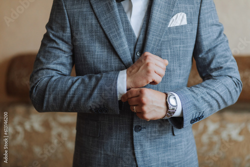 The stylish bridegroom dresses, prepares for the wedding ceremony. The groom's morning. Businessman wears a jacket, male hands closeup, groom getting ready in the morning before wedding ceremony
